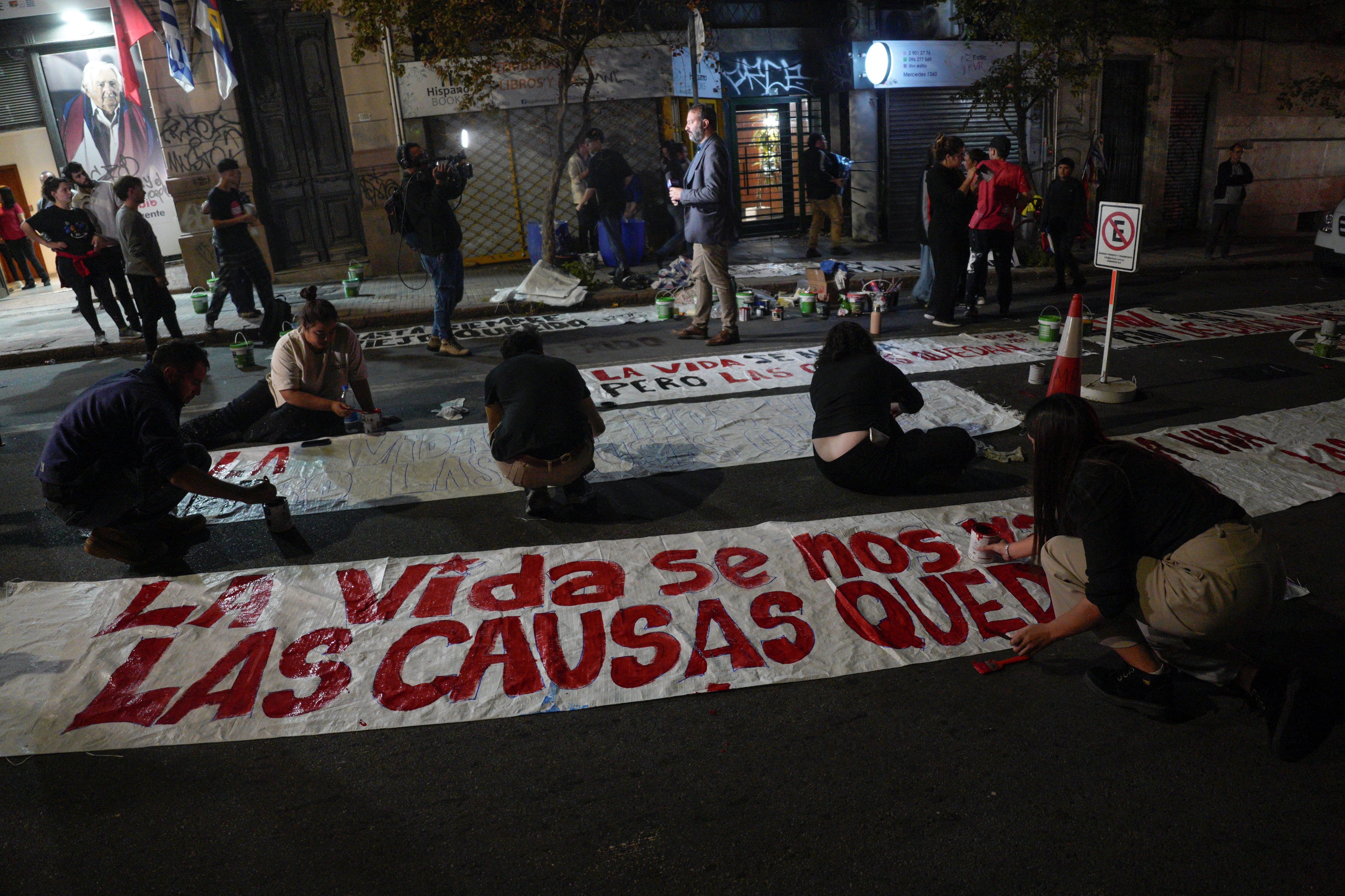 Personas pintan pancartas frente a la sede del Movimiento de Participación Popular (MPP) tras el fallecimiento del expresidente uruguayo José