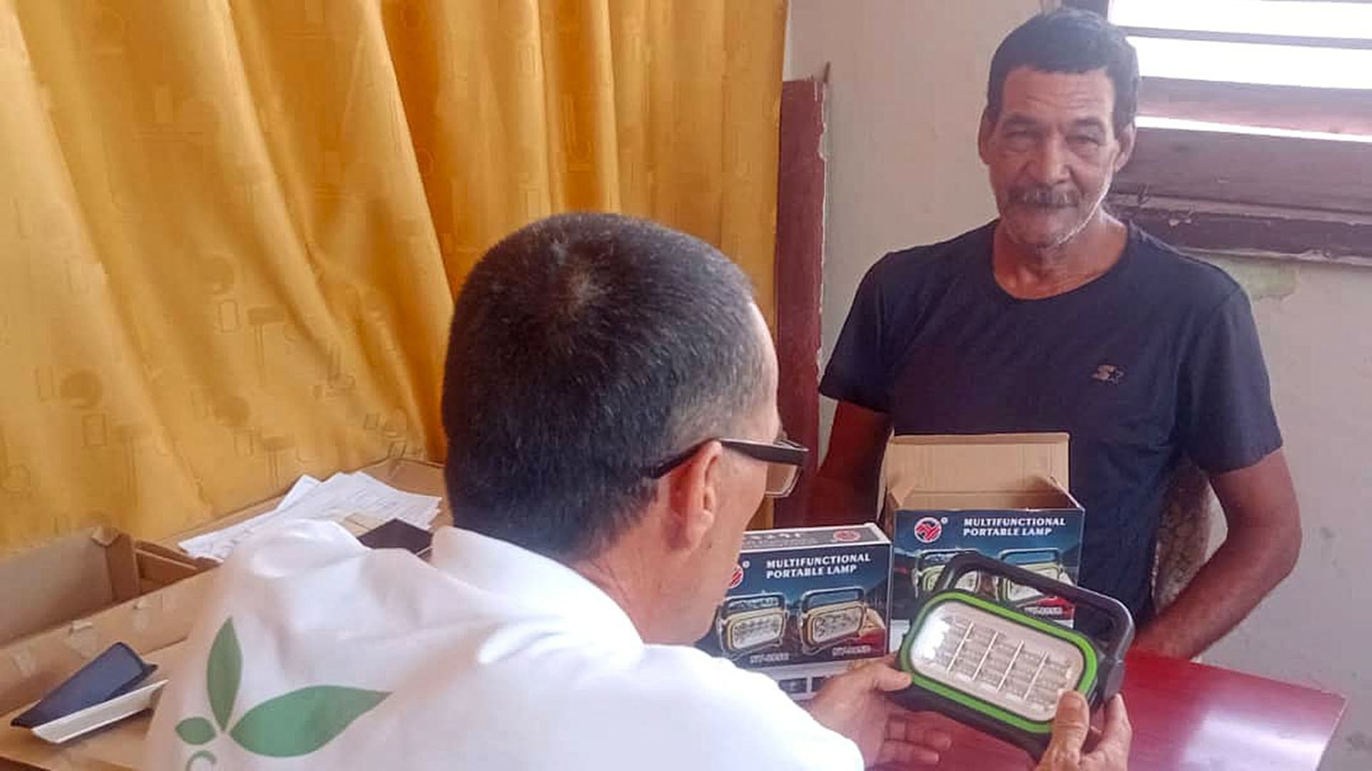 Un funcionario del Programa de las Naciones Unidas para el Desarrollo muestra una lámpara recargable a un ciudadano en Cuba (@PNUDCuba)