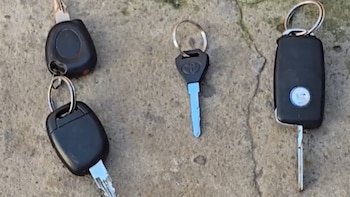 Primer plano de cuatro llaves de vehículos en una superficie de cemento, incluyendo una llave con control remoto y una con el logo de Toyota