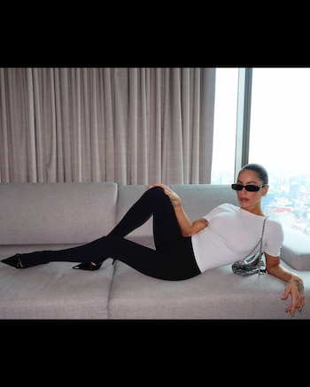 Tini Stoessel, recostada en un sillón gris, con la cartera metálica en la mano