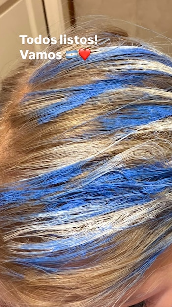 Primer plano de cabello con mechas rubias y azules. Arriba hay un texto blanco que dice 'Todos listos! Vamos' con una bandera de Argentina y un corazón rojo