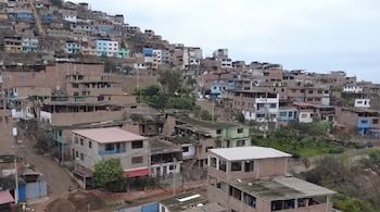 Numerosas casas de diversos materiales y colores se construyen en la ladera de un cerro bajo un cielo nublado