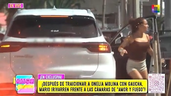 Mujer con top marrón y shorts claros saliendo de un auto oscuro, con un SUV blanco al frente, en una escena callejera diurna