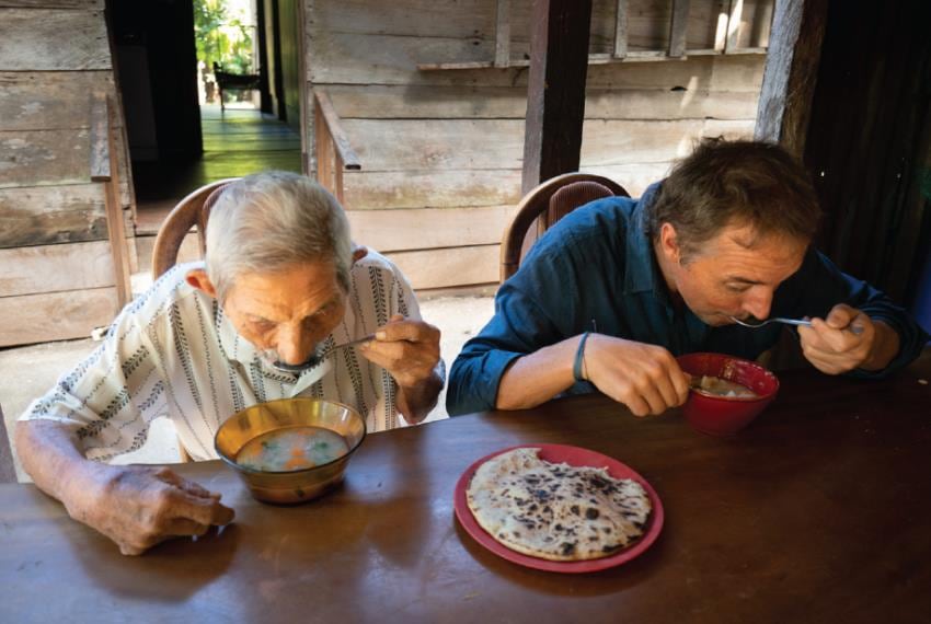 Dan Buettner con un centenario de Nicoya (Costa Rica) comiendo los platos típicos. (Netflix)