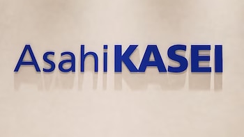 El logotipo corporativo en letras azules de la empresa Asahi Kasei sobre una pared beige