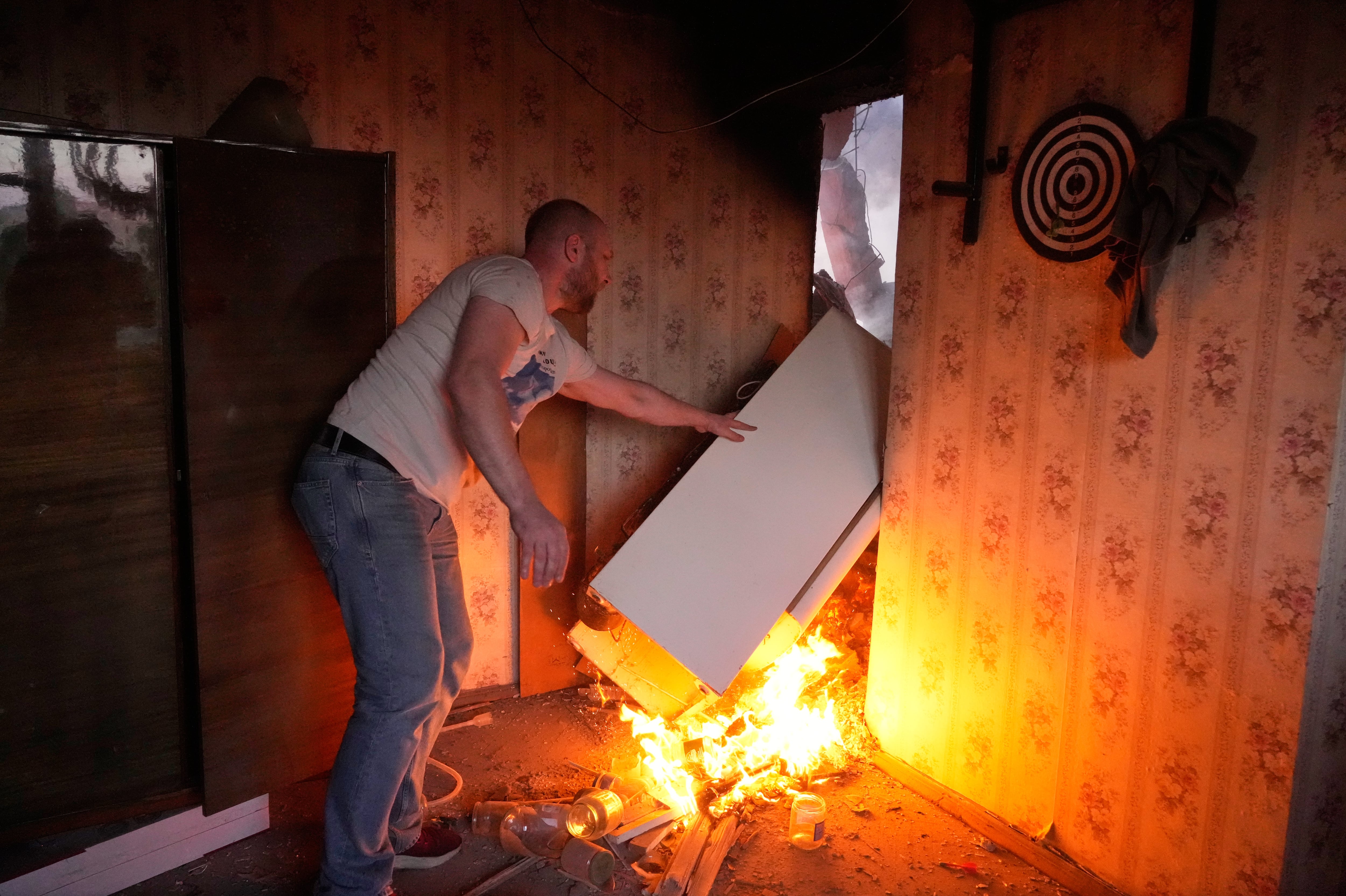Un vecino rescata un refrigerador de entre las llamas tras el ataque ruso del domingo sobre Kiev, en el que se registraron daños en al menos 50 puntos de la capital ucraniana. (AP Photo/Efrem Lukatsky)