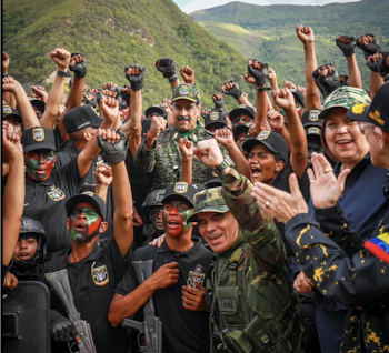 Un grupo de hombres y mujeres, algunos con camuflaje y pintura facial, alzan los puños alrededor de Nicolás Maduro, con un paisaje montañoso de fondo