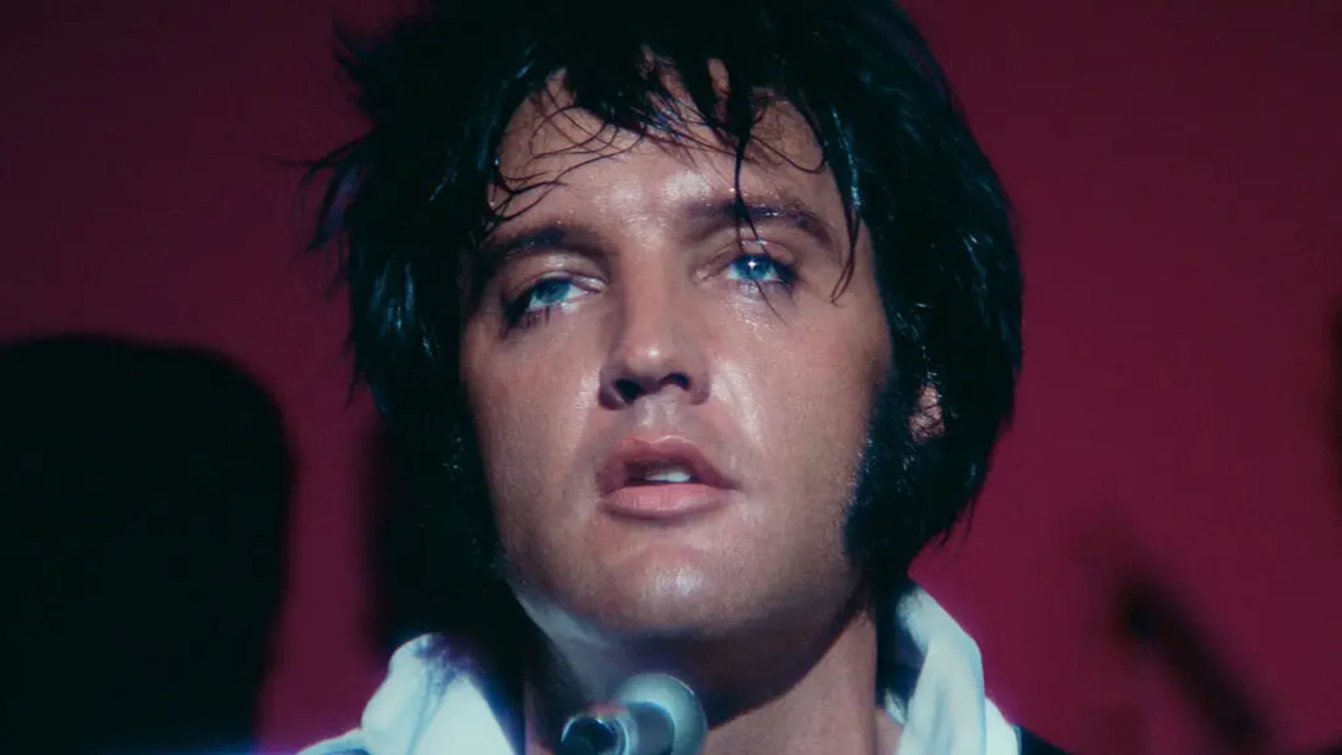 El legendario Elvis Presley visiblemente emocionado y sudoroso durante una apasionada interpretación en uno de sus icónicos conciertos. (Neon)