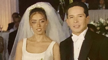 Una mujer con vestido de novia y velo blanco junto a un hombre con traje formal negro y pajarita blanca.