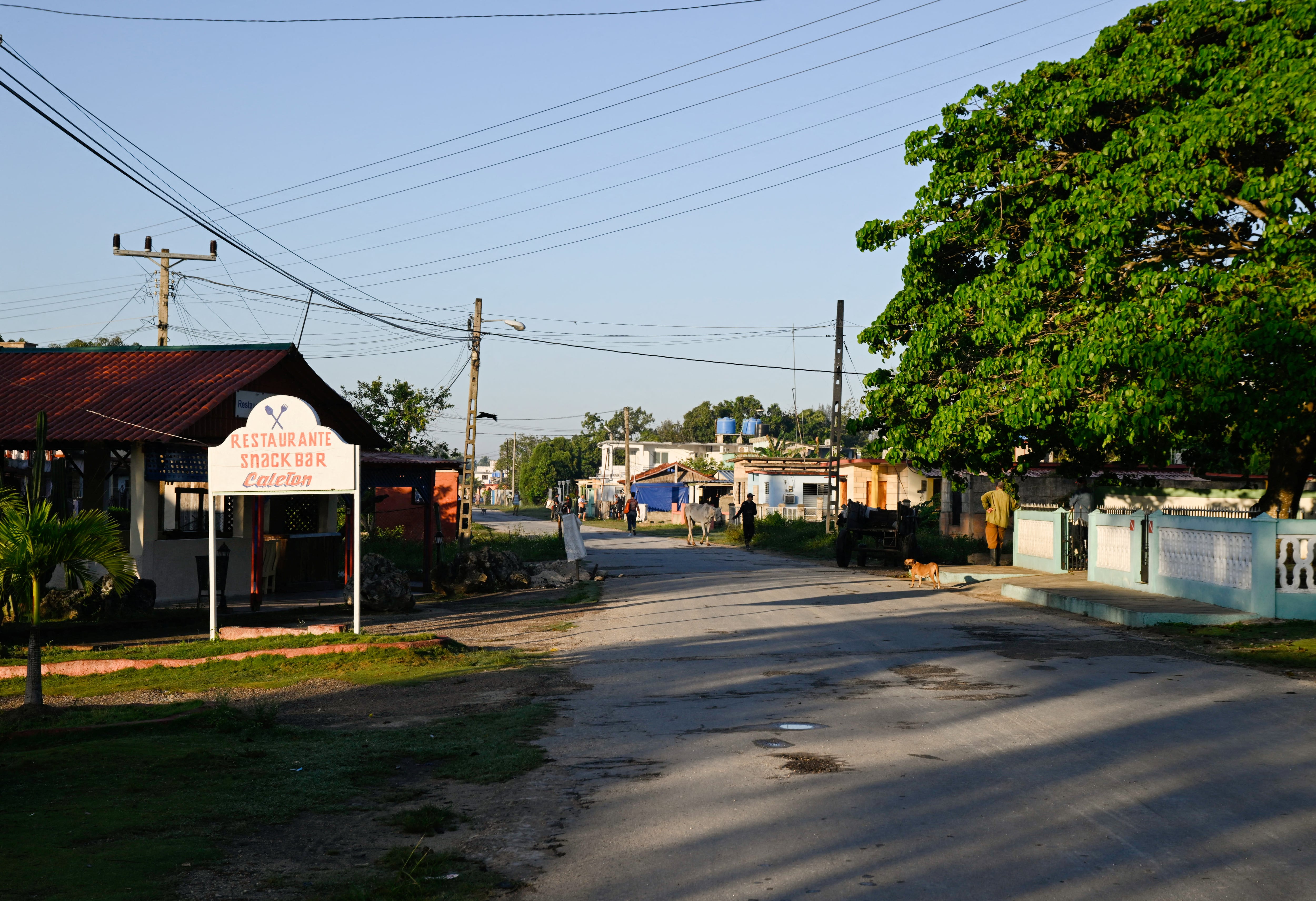 Varias personas pasan junto a un restaurante cerrado mientras los principales destinos turísticos de Cuba permanecen desiertos debido a la escasez de electricidad y combustible provocada por las sanciones estadounidenses. La llegada de turistas internacionales se desplomó un 56 % en febrero con respecto al año anterior, en Playa Larga, Ciénaga de Zapata, Cuba, el 8 de abril de 2026. REUTERS/Norlys Pérez