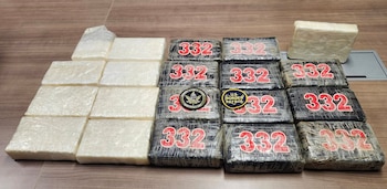 Paquetes empaquetados en plástico blanco y negro con el número 332 en rojo e insignias policiales sobre una mesa de madera