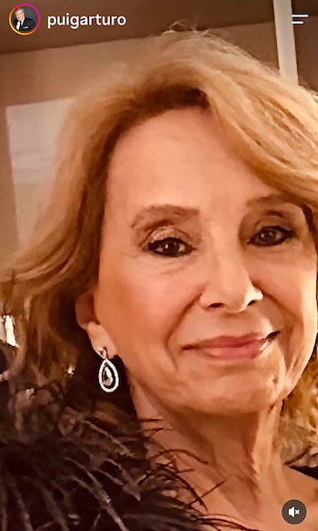 Retrato de cerca de Selva Alemán sonriendo, con cabello claro ondulado, aros colgantes y atuendo oscuro