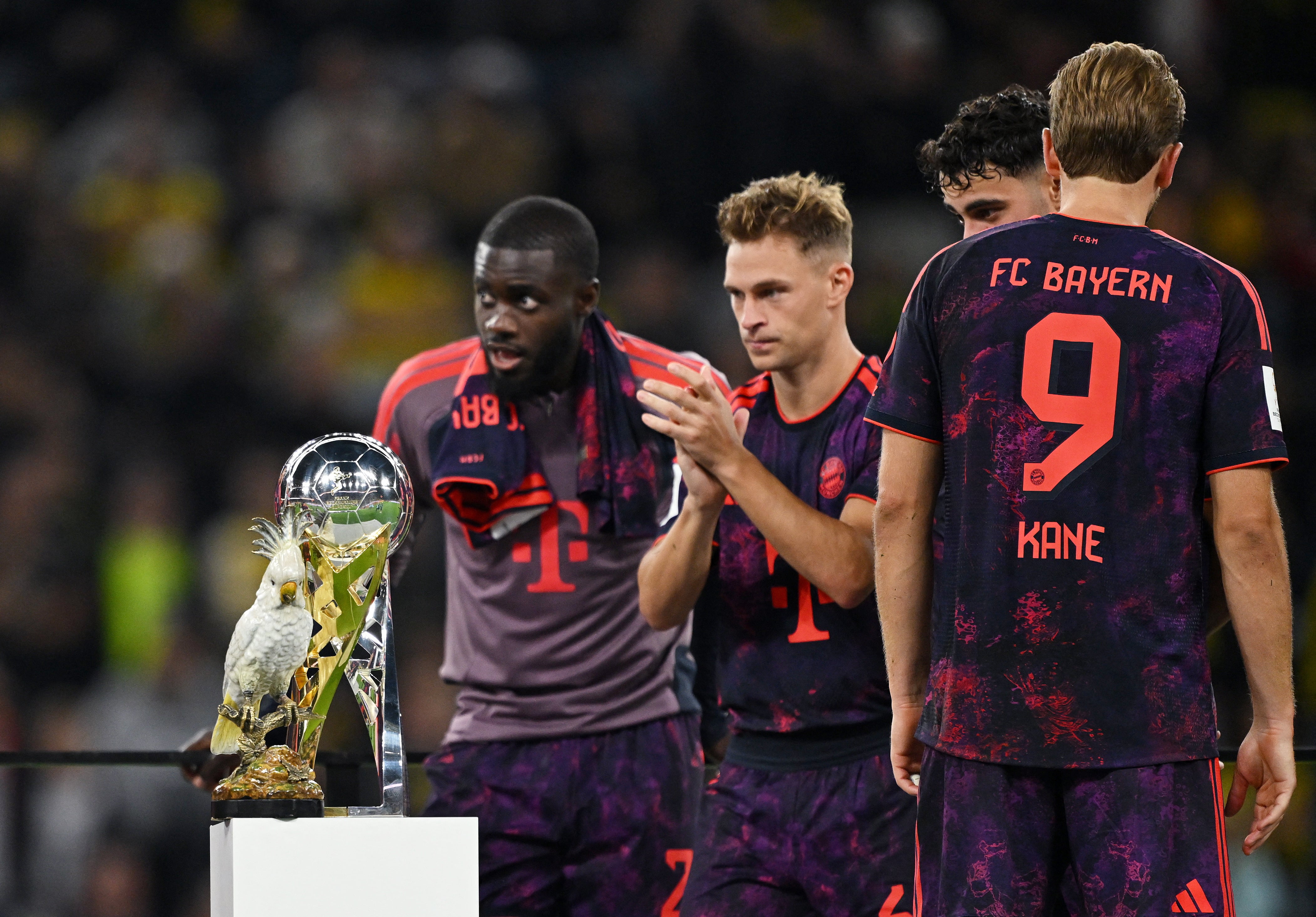 Harry Kane, Joshua Kimmich y Dayot Upamecano, del Bayern Múnich, observan el trofeo de la Supercopa DFL y la cacatúa de porcelana durante la premiación tras la victoria en la final-crédito Teresa Kroeger/REUTERS