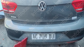 Parte posterior de un coche gris marca Volkswagen Fox con las luces traseras rojas y la placa borrosa.