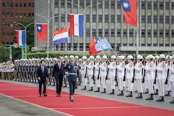 Presidentes Santiago Peña y Lai Ching-te, con un oficial, caminan sobre alfombra roja flanqueados por guardias de honor. Banderas de Taiwán y Paraguay visibles
