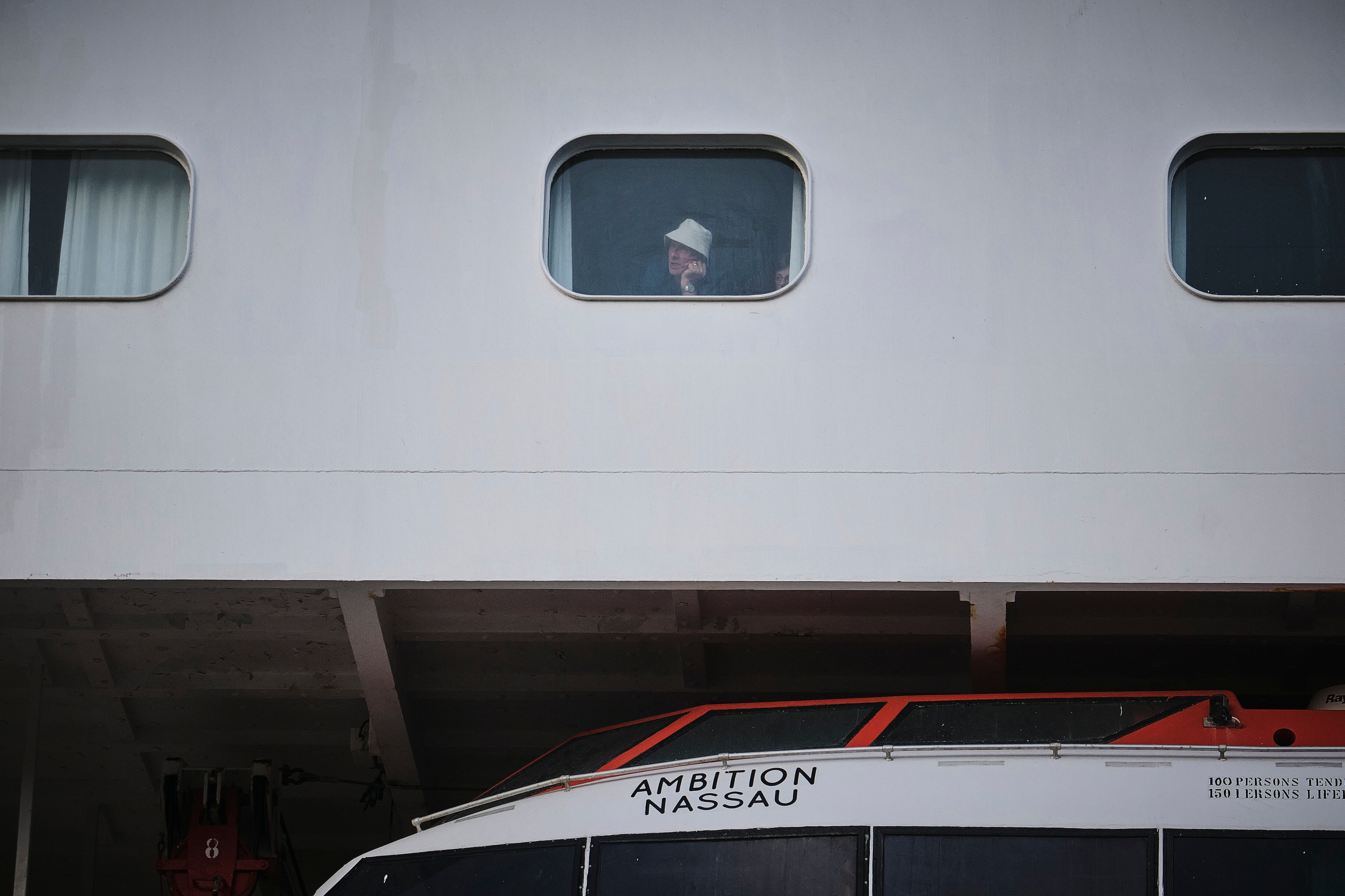 Un pasajero mira por la ventana del crucero Ambition, atracado en Burdeos. (Guillaume Pinon/EFE/EPA)