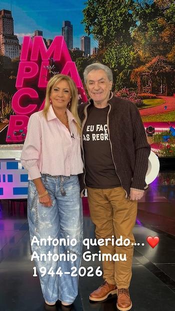 Una mujer y un hombre de pie en un estudio de televisión frente a una pantalla brillante, con un texto superpuesto en la parte inferior