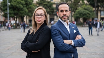 Adriana Cely y Abelardo de la Espriella de pie, espalda con espalda, con los brazos cruzados, mirando al frente en un entorno urbano al aire libre.