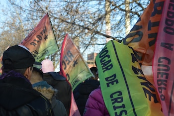 Monumento metálico del Papa Francisco sonriendo y saludando, sobre una base amarilla con el texto "PAPA FRANCISCO". Personas y estatuas religiosas alrededor