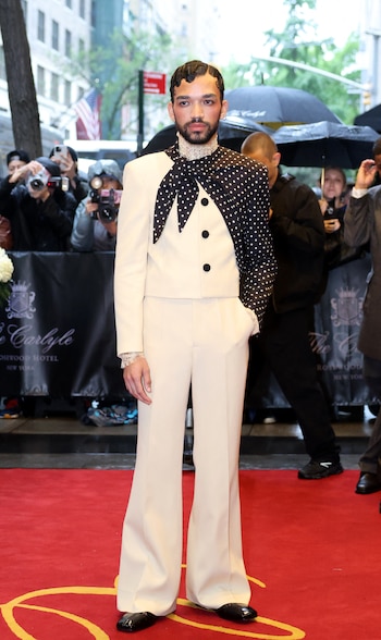 El actor Justice Smith con un conjunto bicolor en marfil y negro, con chaqueta corta de silueta estructurada y tres botones frontales, combinada con un pantalón de pierna ancha a juego