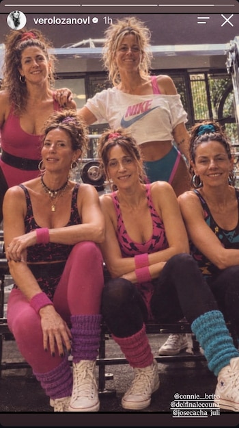 Cinco mujeres con vestimenta deportiva retro de varios colores, mallas, calentadores y peinados con colas de caballo