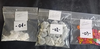 Tres bolsas transparentes con etiquetas, una con polvo blanco, otra con paquetes envueltos y la tercera con globos de colores, sobre superficie oscura
