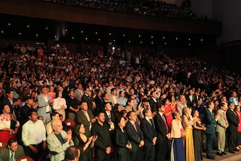Una multitud diversa de personas aplaudiendo en las gradas de un auditorio oscuro y amplio durante una ceremonia de premiación