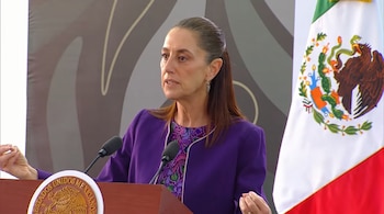 Claudia Sheinbaum habla frente a un micrófono en un estrado con el escudo de Estados Unidos Mexicanos y la bandera nacional.