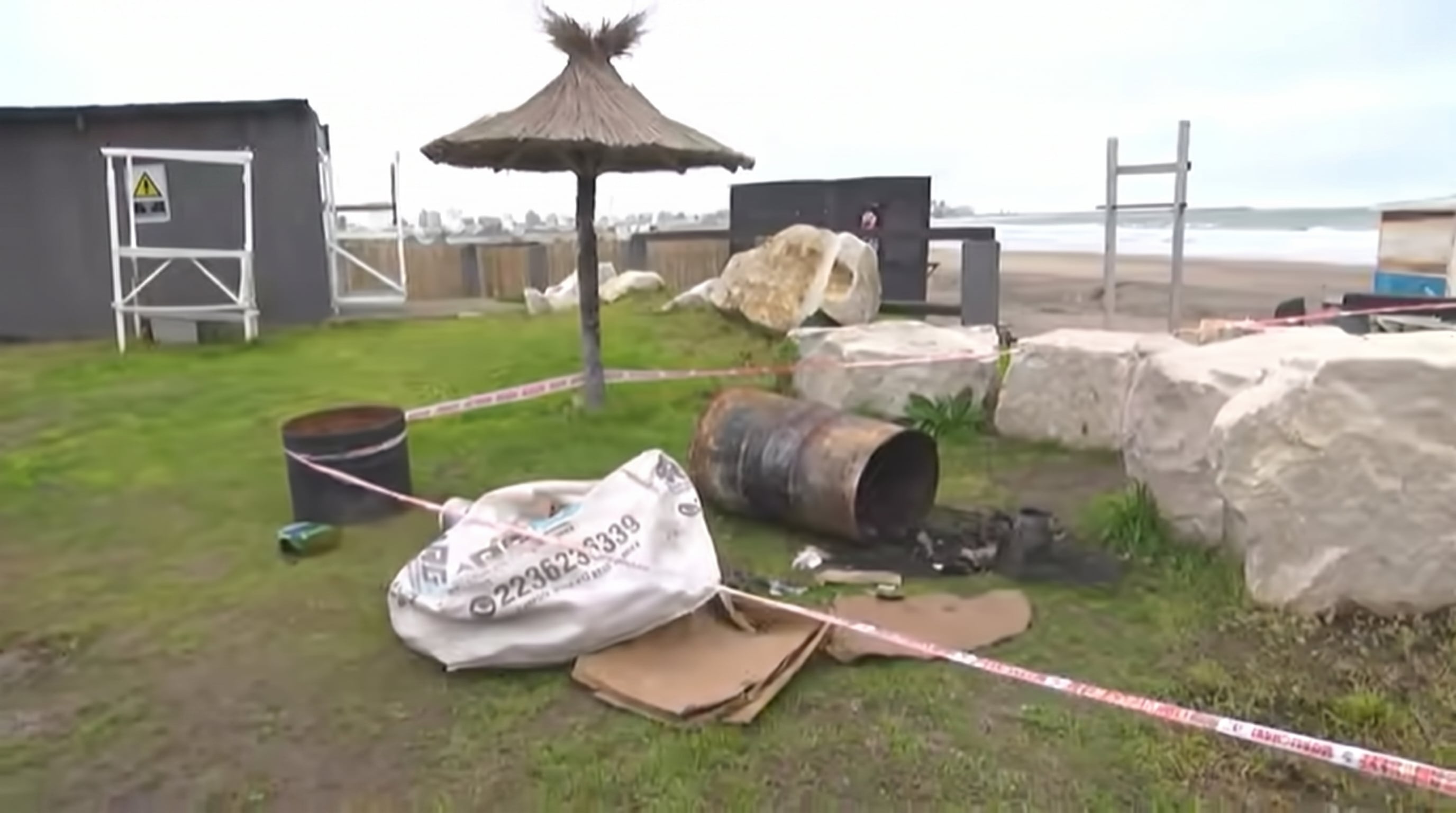 El tacho donde quemaban cosas junto a una sombrilla de paja