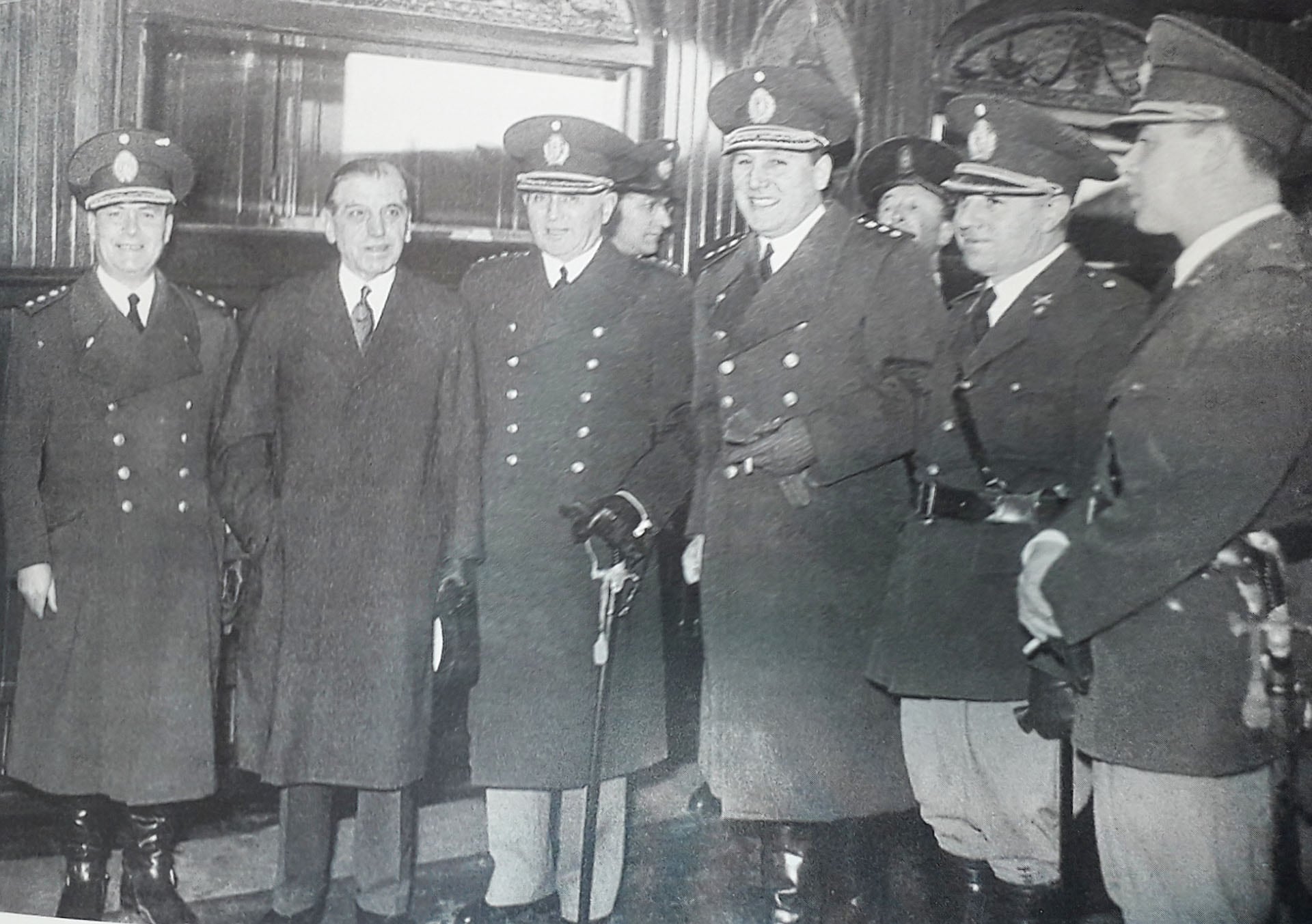 Una imagen de 1947, en la que el presidente Perón está en el centro, sosteniendo un cigarrillo con la mano enguantada. Savio es el segundo, desde la derecha