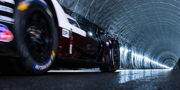 Automóvil de carreras blanco y rojo en el interior de un túnel oscuro. La imagen muestra la rueda delantera izquierda y parte del costado del vehículo