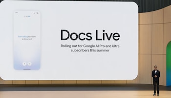 Sundar Pichai, CEO de Google, de pie junto a una gran pantalla que muestra "Docs Live" y un teléfono móvil con la opción de dictado