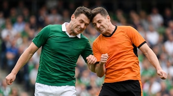 Dos atletas masculinos chocan sus cabezas. Uno lleva camiseta verde y el otro camiseta naranja. Ambos tienen los puños cerrados. Fondo con espectadores desenfocados.