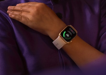 Primer plano del brazo de una persona con piel morena vistiendo una camisa morada, mostrando un smartwatch Huawei Luca-B19 con pantalla encendida en su muñeca