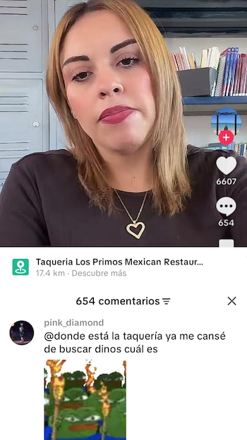 Mujer de cabello rubio, blusa negra y collar de corazón dorado, mirando a cámara, con un fondo de casilleros y estantes de libros; parte de la interfaz de TikTok visible