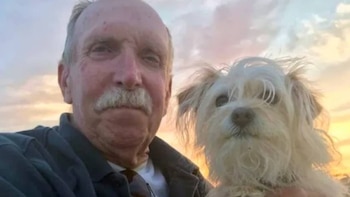 Retrato de um homem barbudo segurando um cachorro maltês branco. Ao fundo, um céu com nuvens coloridas ao pôr do sol