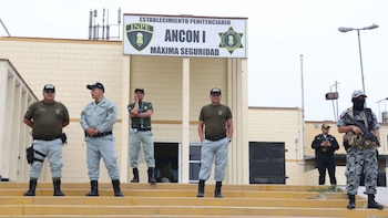 Agentes con uniformes tácticos y de custodia permanecen de pie en las escaleras de acceso a un establecimiento penitenciario de máxima seguridad