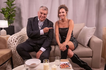 Luis Ventura, con traje oscuro, señala a Pampita, quien sonríe sentada a su derecha con vestido negro y botas. Ambos en un sofá frente a una mesa con velas