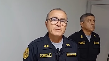 Dos oficiales de la Policía Nacional del Perú con uniforme oscuro, uno con gafas y nombre J. Quiroz D., el otro con nombre J. Reyes D., frente a una pared clara