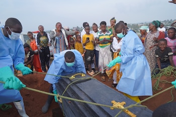 Varias personas vestidas con equipos de protección bajan a una tumba el féretro de Jeannine Katusabe, quien murió de ébola, durante su entierro en Bunia, en la provincia de Ituri, en el este de República Democrática del Congo. (AP Foto/Dieudonne Dirole)