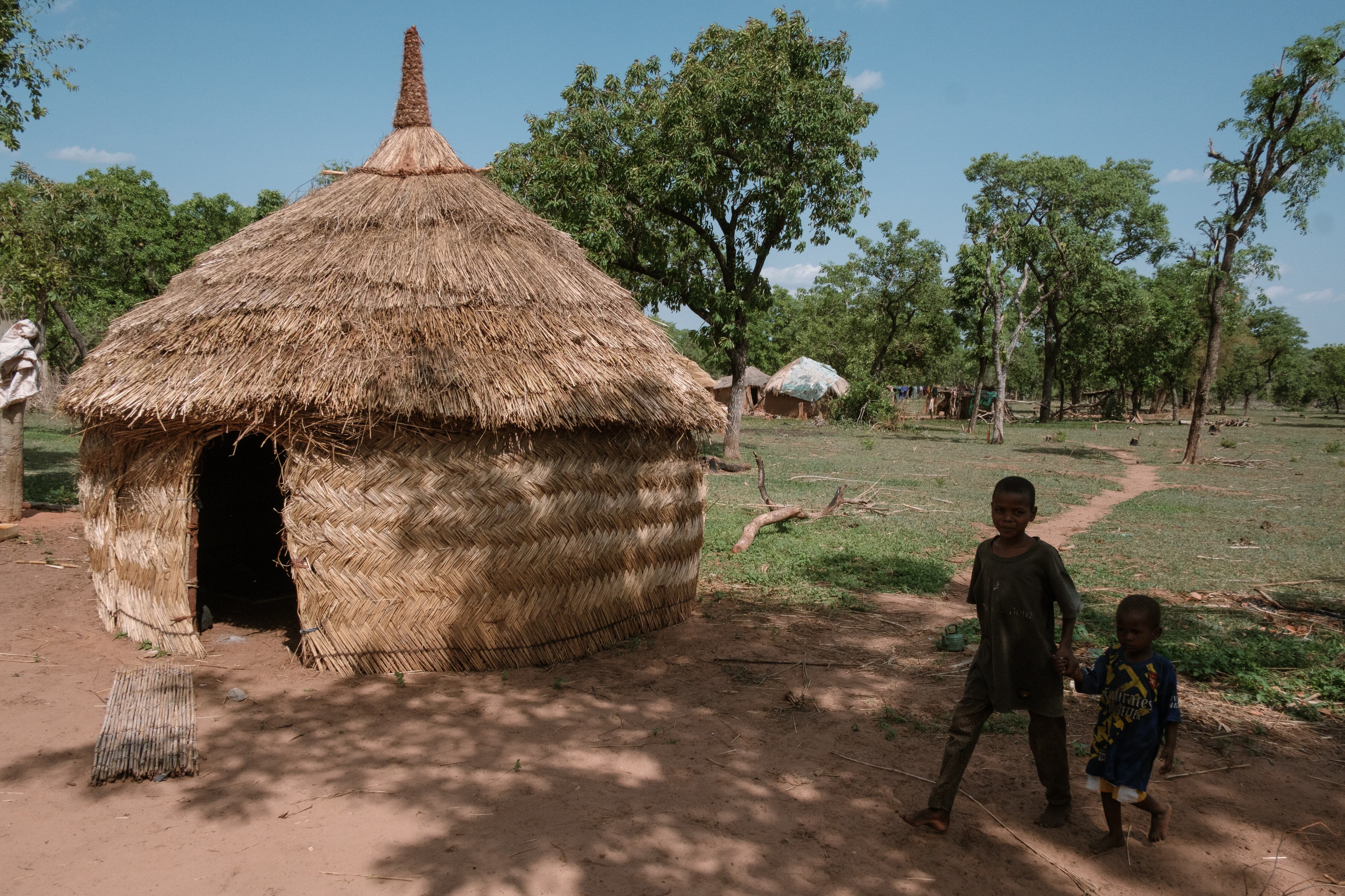 Unos niños pasan junto a una choza en Daboya, Ghana, una aldea creada por refugiados burkineses que huyen de la violencia (Guy Peterson/Para The Washington Post)