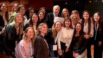 Un grupo de personas rodea al doctor Alberto Cormillot, quien sostiene un certificado enmarcado en un salón