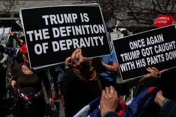 Un manifestante anti-Trump sostiene pancartas