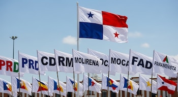 Bandera de Panamá ondeando sobre varias banderas blancas con siglas y logotipos de partidos políticos: PRD, CD, RM, MOLIRENA, MOCA, FAD, Panameñista.