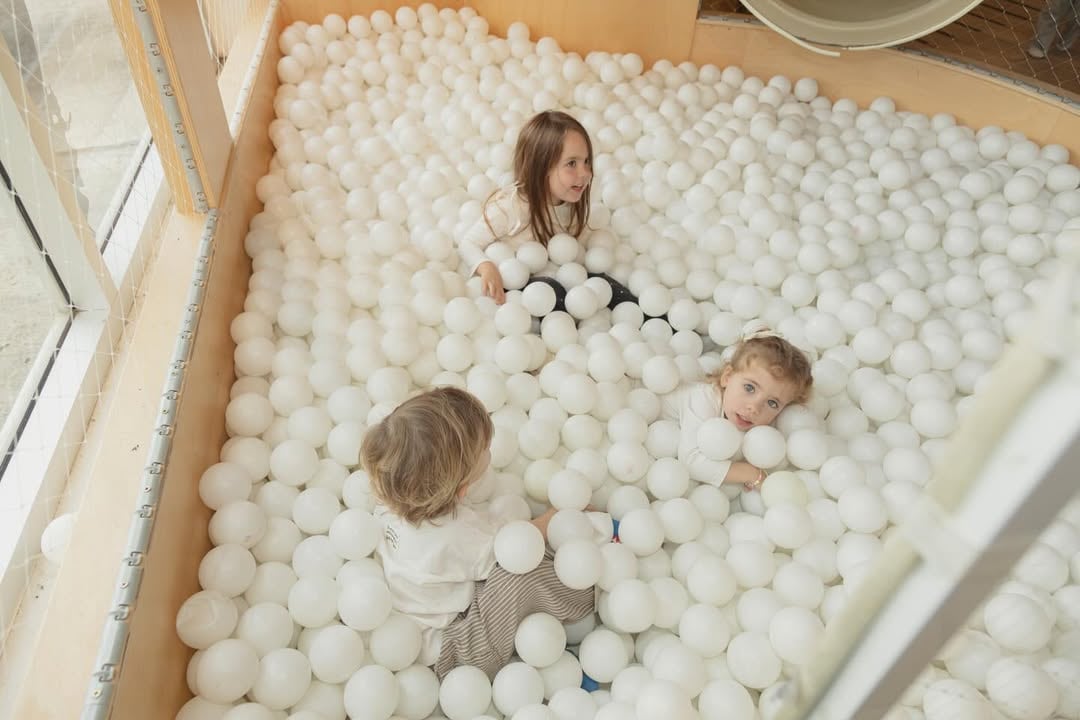 Los niños disfrutaron de áreas de juego como una piscina de pelotas blancas y un trampolín decorado con figuras geométricas