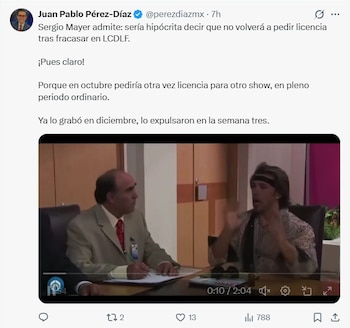 Captura de pantalla de un video mostrando a dos hombres sentados en una mesa, uno en traje escribiendo y el otro con pañuelo en la cabeza gesticulando