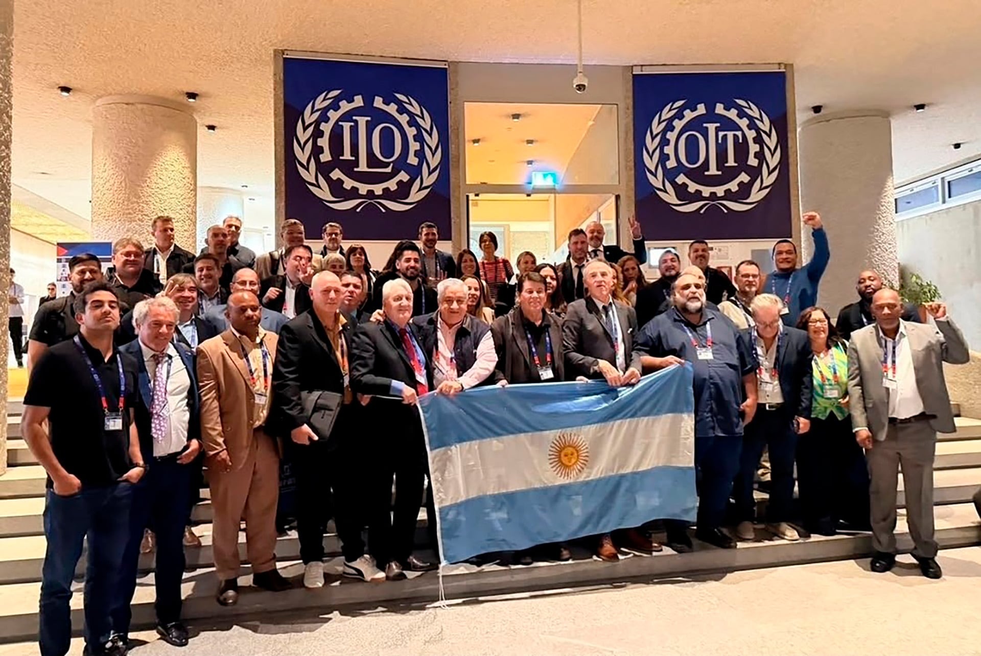 La delegación de la CGT argentina posa con la bandera nacional en la conferencia anual de la Organización Internacional del Trabajo (OIT), destacando su participación en el evento global.