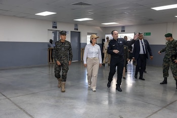 Keiko Fujimori camina por una sala amplia con piso de cemento junto a militares y funcionarios salvadoreños dentro de un penal