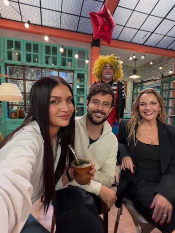 Zaira Nara, un hombre barbudo con mate y una mujer sonríen en un set de televisión con un payaso en el fondo, luces y un globo rojo
