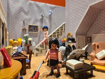 Cuatro figuras PLAYMOBIL: una mujer aspira, un hombre lee un periódico, una mujer sube una escalera y otra mujer está sentada